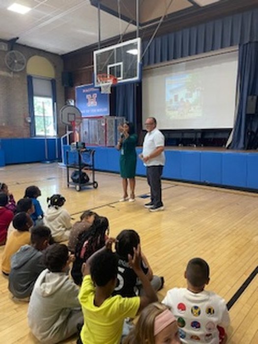Edward Rodriguez and a school staff member beside the screen showing a book illustration
