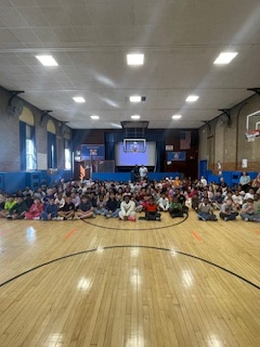 Full gymnasium of students seated for the author presentation