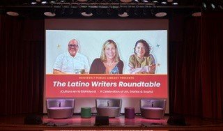 Empty stage set for the Latino Writers Roundtable with the panelists' photos projected on screen